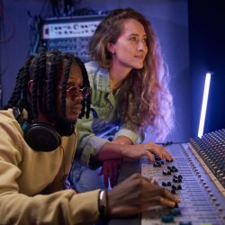 African sound engineer using sound record to write music with his assistant in the music studio