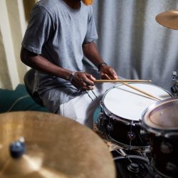 Young man with drumsticks recording his music in home studio